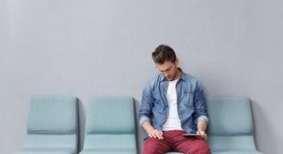 young-man-sitting-waiting-room-holding-tablet